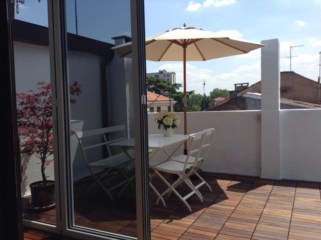 einen Balkon mit einem Tisch und einem Sonnenschirm in der Unterkunft La mansardina in Padua