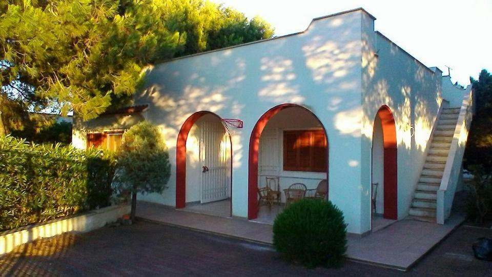 a white house with red arches and a patio at Villa Brigida in Manduria