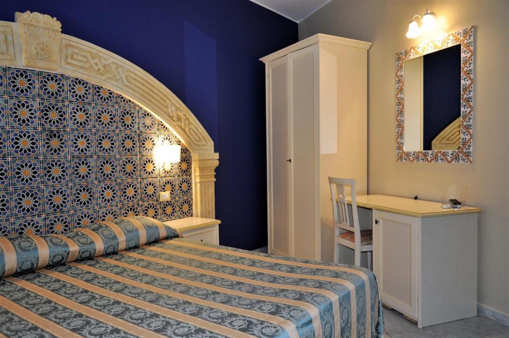 a bedroom with a bed with a blue wall at Al-Tair in San Vito lo Capo