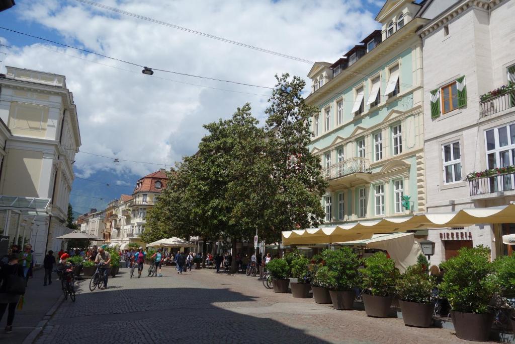 uma rua da cidade com edifícios e pessoas em bicicletas em Hager Apartment em Merano