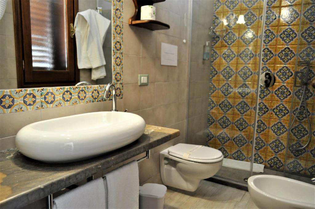 a bathroom with a white sink and a toilet at Al-Tair in San Vito lo Capo