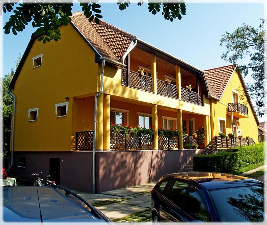 una casa amarilla con un coche aparcado delante de ella en Gulyás Vendégház, en Tiszafüred