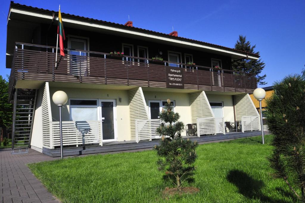 un edificio con un balcón con una bandera. en Apartamentai Trys pušys, en Šventoji