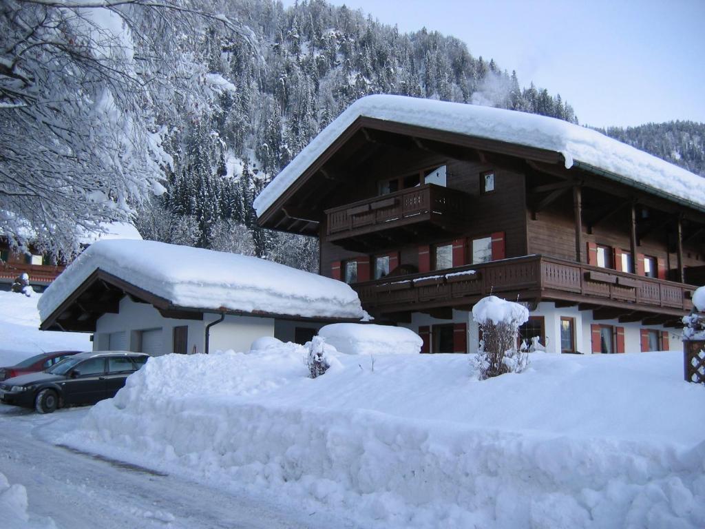 a snow covered building with a car parked in front at Ferienwohnungen Marietta in Reit im Winkl