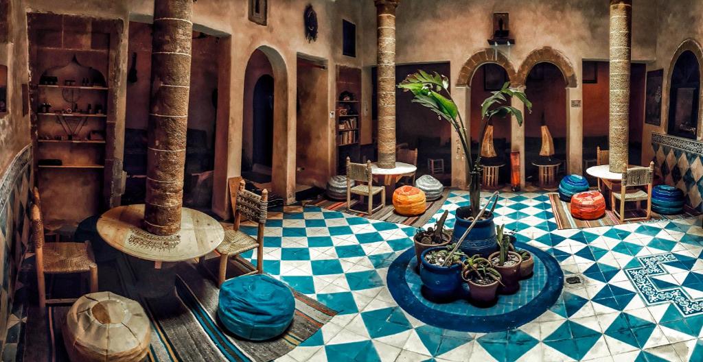 エッサウィラにあるザ チル アート ホステルの青と白のチェッカーの床とヤシの木があるお部屋