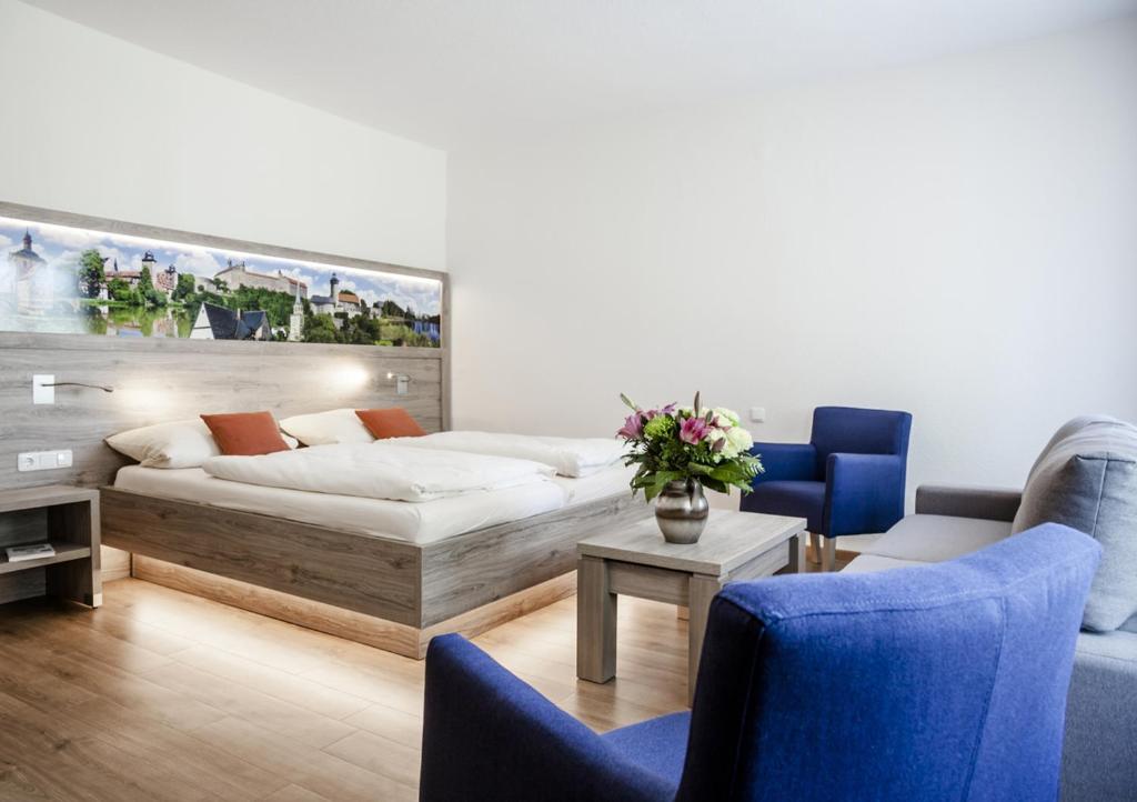Hotel Ertl في كولمباخ: غرفة معيشة مع سرير وكرسيين