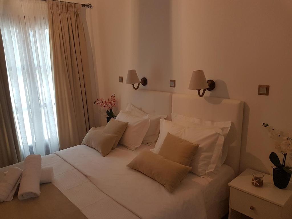a white bedroom with a large white bed with pillows at Santorini Family Apartments in Kamari