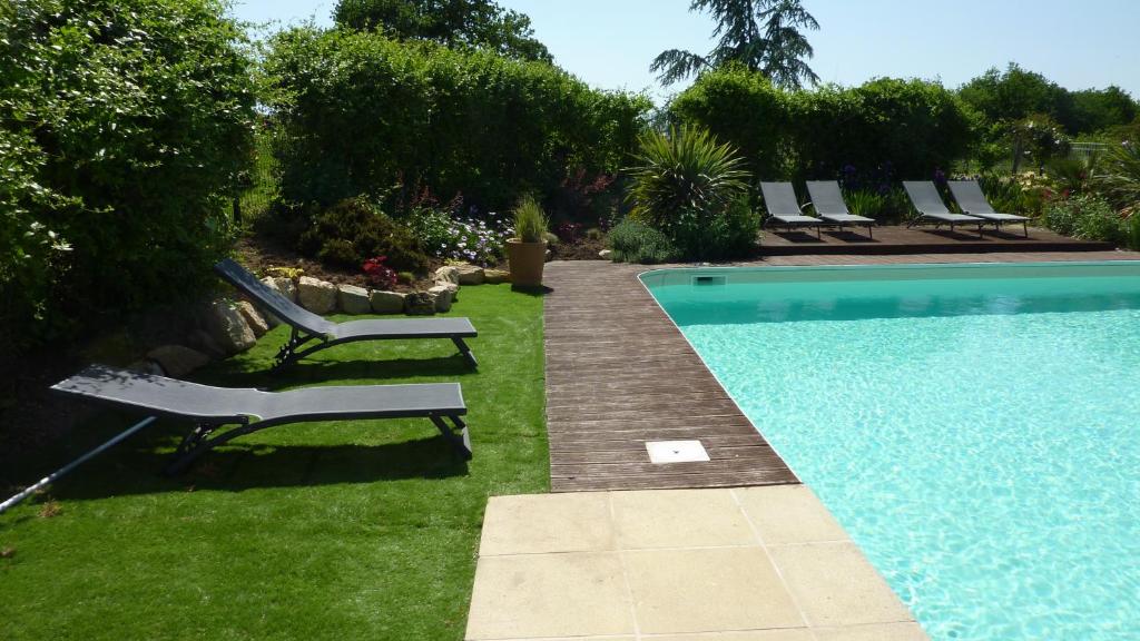 una piscina en un patio con tumbonas en La Boisnière, en Mouilleron-en-Pareds