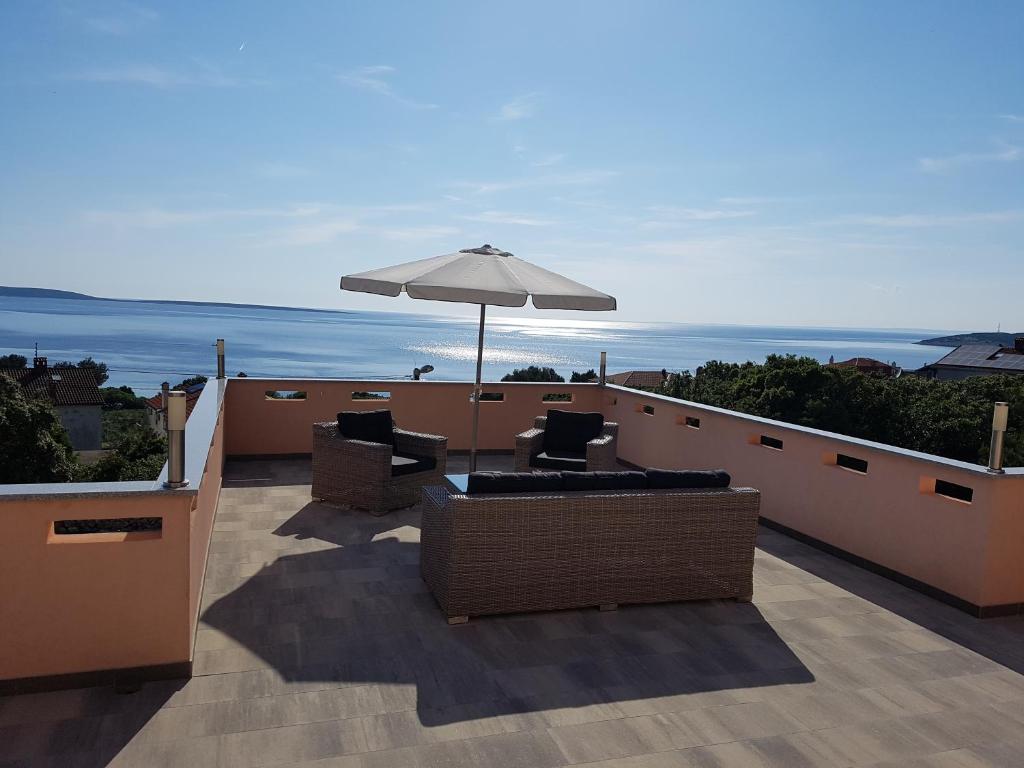 a patio with chairs and an umbrella on a roof at Apartmani Ivana in Cres