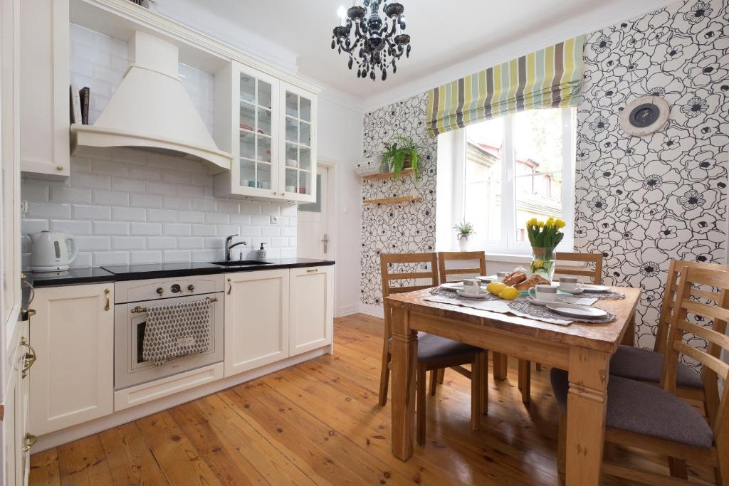 une cuisine avec des armoires blanches et une table en bois dans l'établissement Prosta Apartment Old Town, à Olsztyn