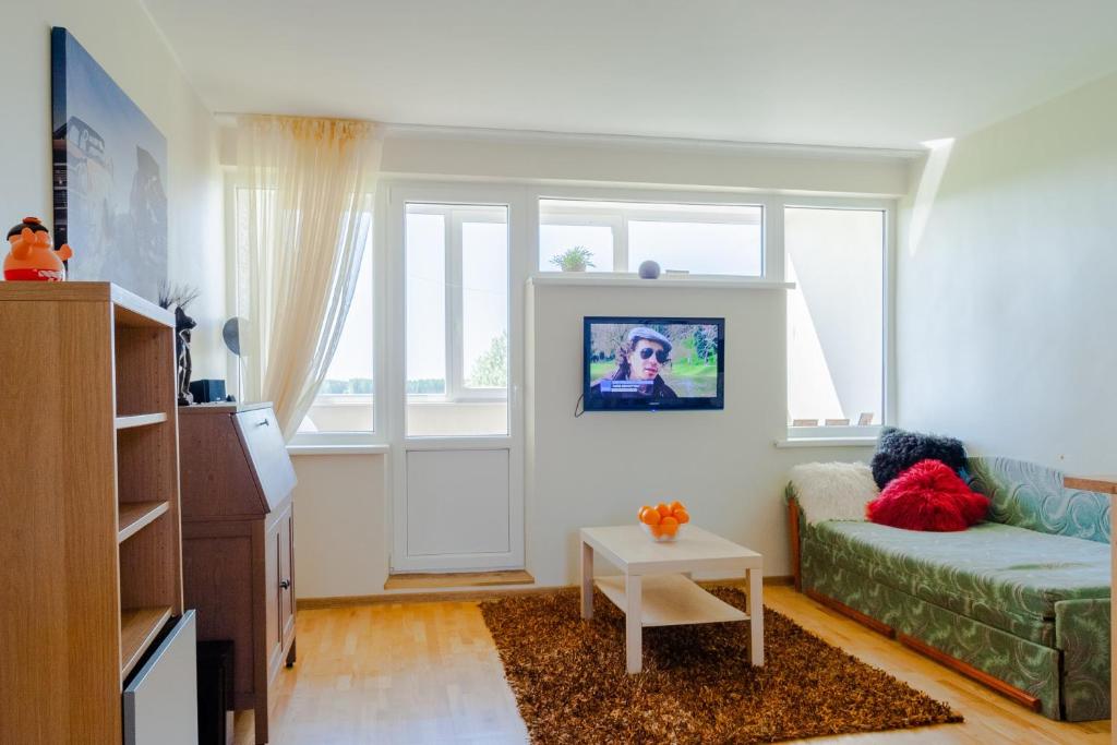 a living room with a couch and a window at White camomile condo in Šventoji