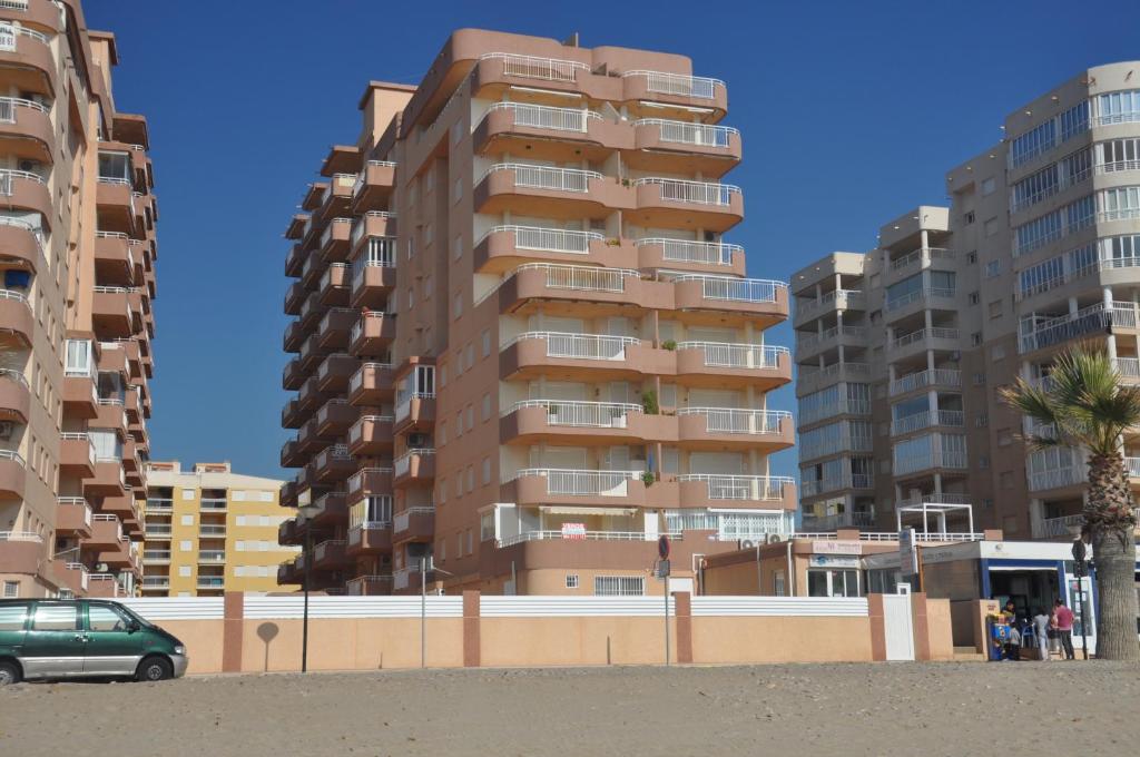 wysoki budynek apartamentowy z samochodem zaparkowanym przed nim w obiekcie Daytona Vidaber Primera línea w mieście Oropesa del Mar