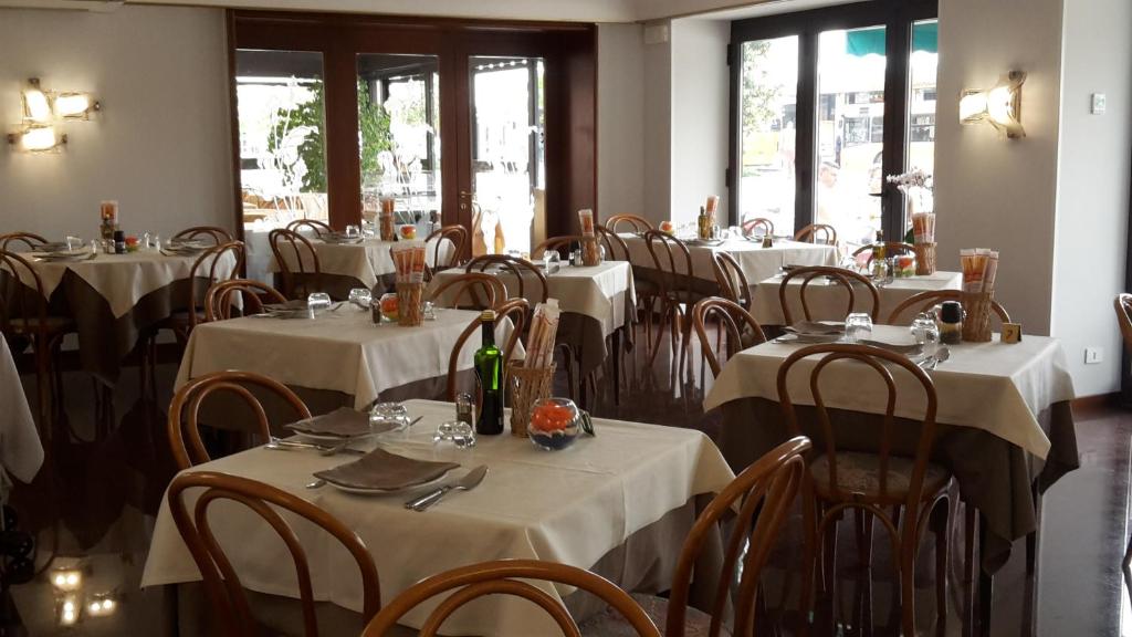 a restaurant with white tables and chairs and windows at Hotel Belvedere in Venice-Lido
