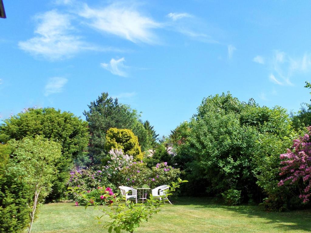 zwei weiße Bänke in einem Garten mit Blumen und Bäumen in der Unterkunft VILLA FREIA Dresden - Exklusive Ferienwohnung zum Erholen & Entspannen in Dresden