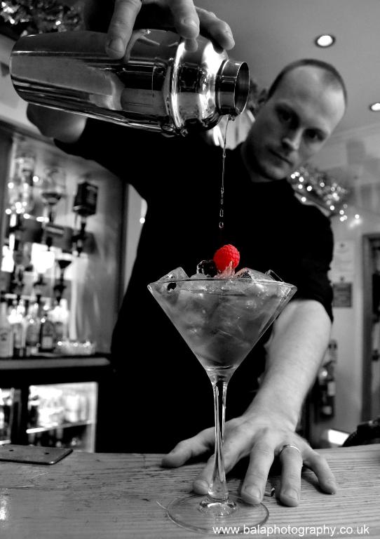a man pouring a drink into a martini glass at The Riviera Hotel & Apartments - Alum Chine in Bournemouth