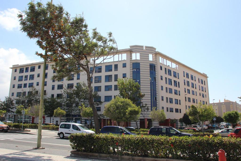 een groot wit gebouw met auto's geparkeerd op een parkeerplaats bij Blue House in Las Palmas de Gran Canaria