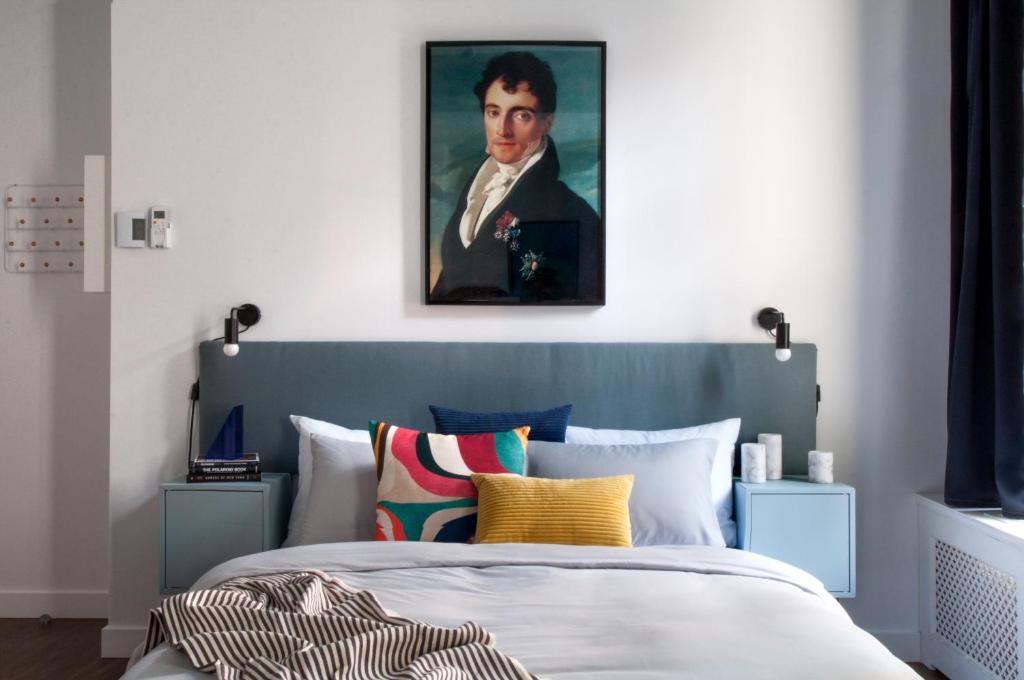 a bedroom with a bed with a painting of a man at Maison Saint-Vincent By Maisons & co in Montréal