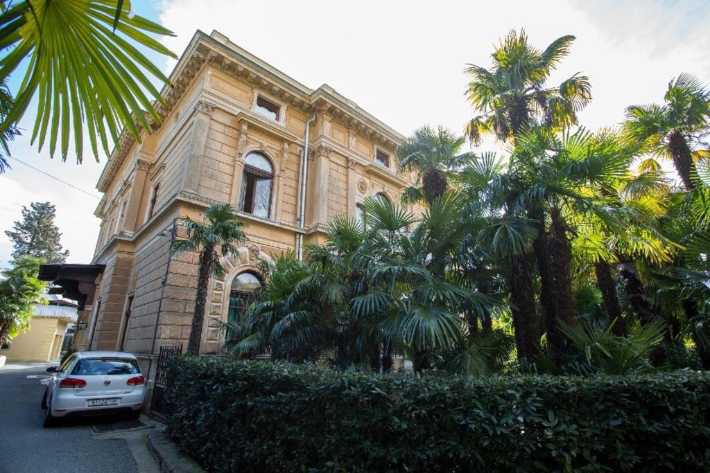a car parked in front of a building with palm trees at Villa Penkala Apartment in Opatija