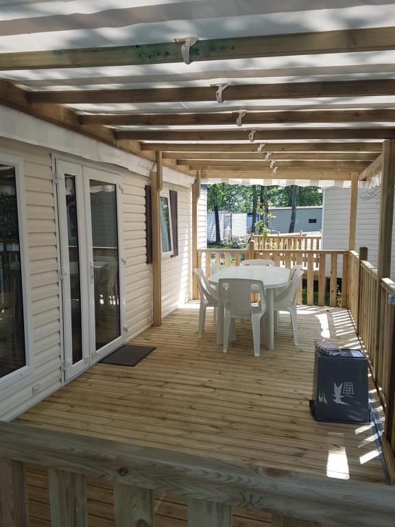 une terrasse en bois avec une table et des chaises. dans l'établissement Mobil Home Soulac, à Soulac-sur-Mer