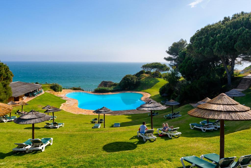 a view of a pool with umbrellas and the ocean at Blue Apartment in Prainha in Alvor