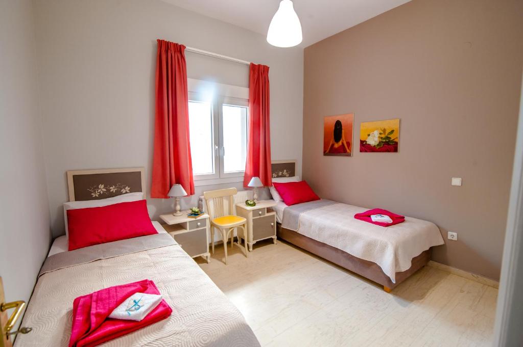 スタロスにあるSkandalakis Homes & Apartmentsのベッドルーム1室(ベッド2台付)、赤いカーテン付きの窓が備わります。