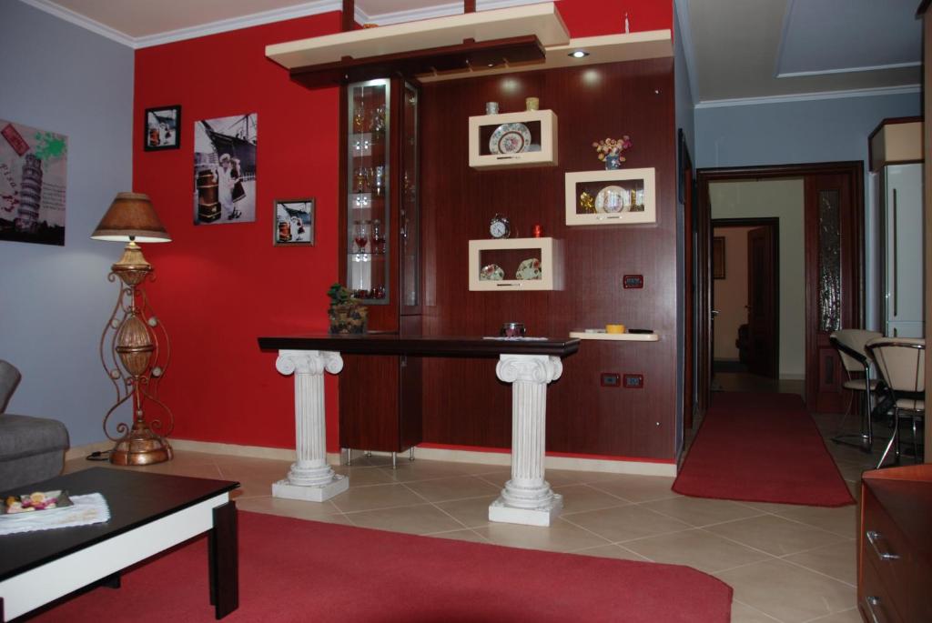 una sala de estar con una pared roja y una mesa. en Villa Alfred en Sarandë