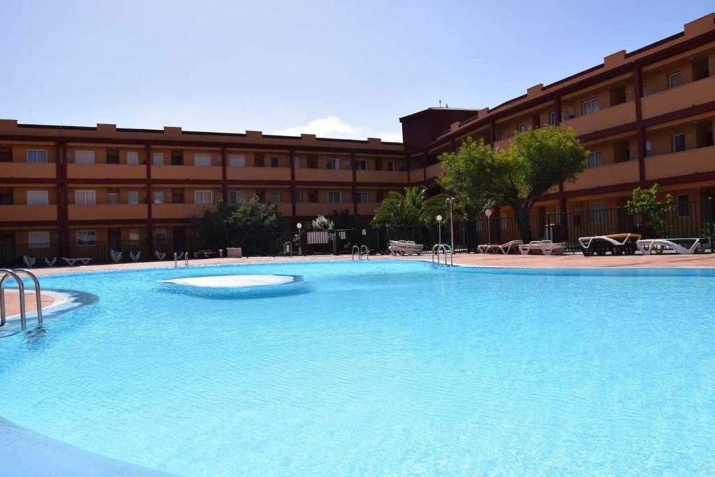 una grande piscina di fronte a un edificio di Caleta Relax - Apartamento Fuerteventura Apartment a La Oliva