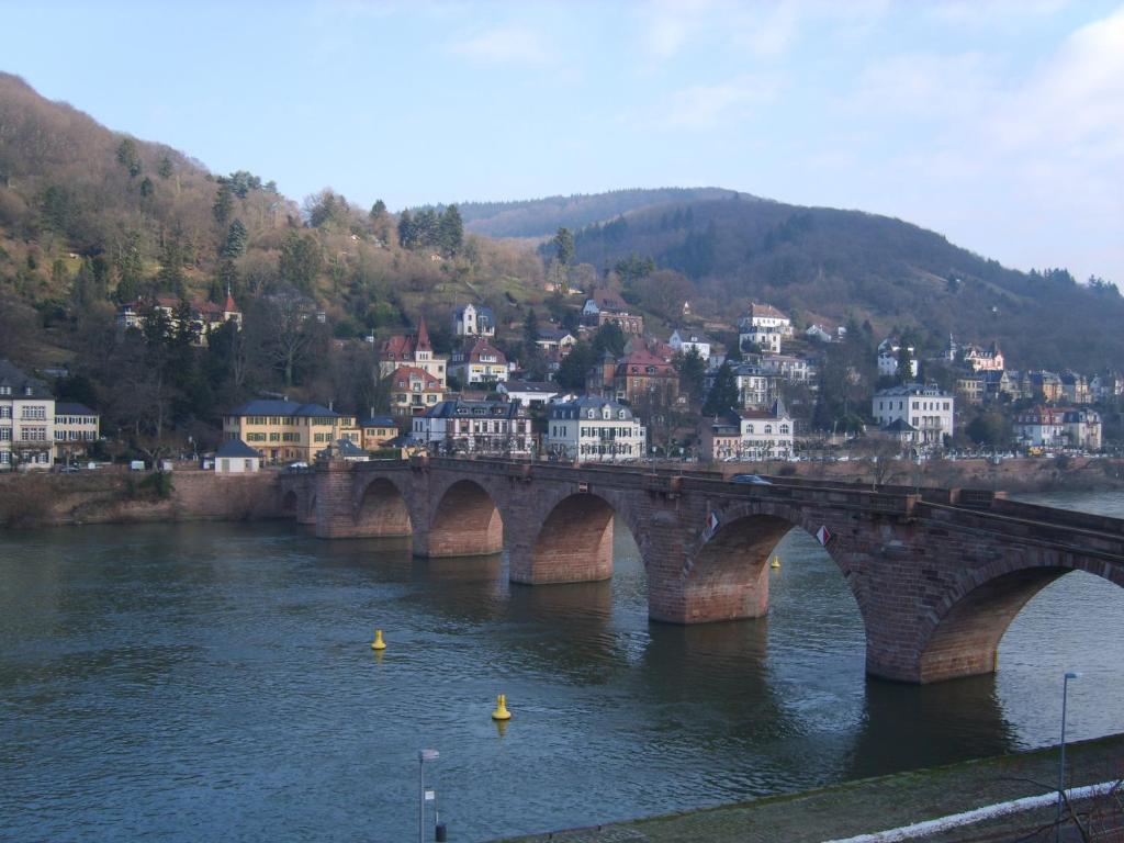 eine Brücke über einen Fluss mit einer Stadt im Hintergrund in der Unterkunft Vier Jahreszeiten in Heidelberg