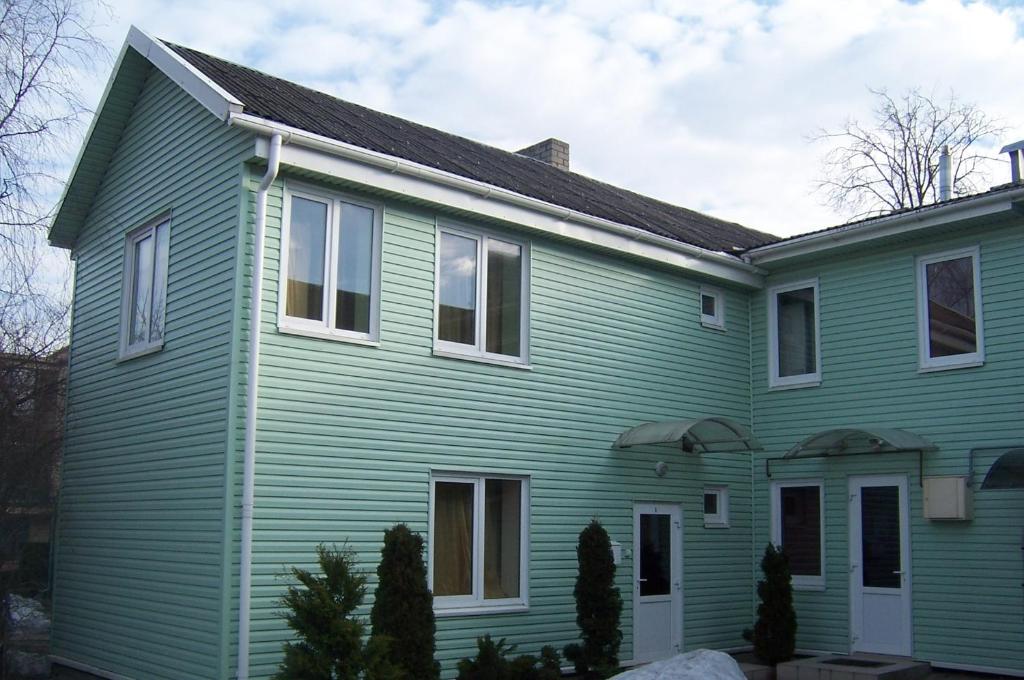 a green house with a black roof at Guest house Rasa in Palanga