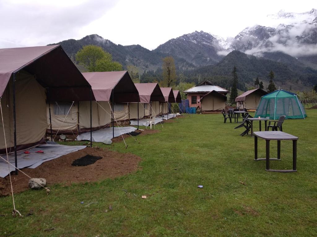 uma fileira de tendas num campo com montanhas em Aru Eco Resort em Pahalgām