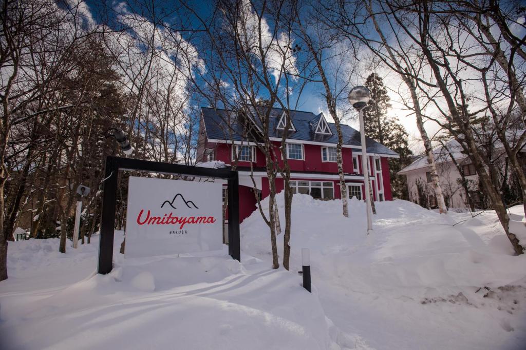 a red house with a sign in the snow at Umitoyama Hakuba in Hakuba