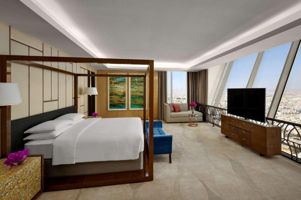 a bedroom with a bed and a television and a balcony at Hyatt Regency Riyadh Olaya in Riyadh