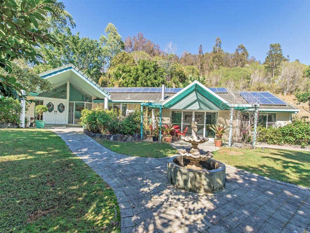 ein Haus mit einem Brunnen im Vorgarten in der Unterkunft Noosa Hinterland Spectacular Boutique Guesthouse in Cooran