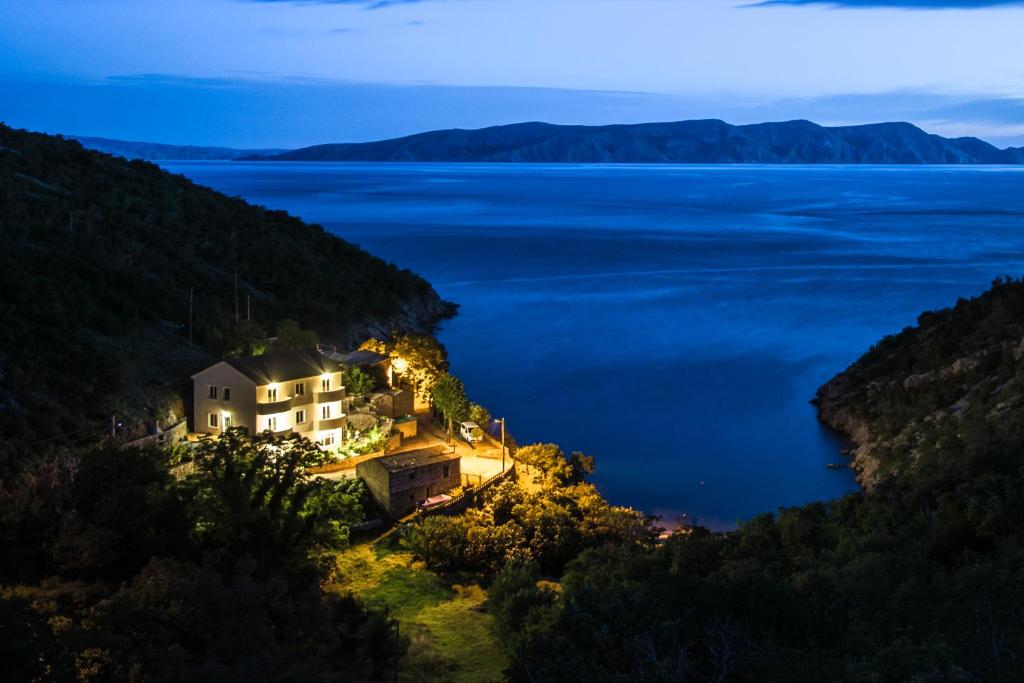 a house on a hill overlooking the water at night at Dora Apartment in Senj