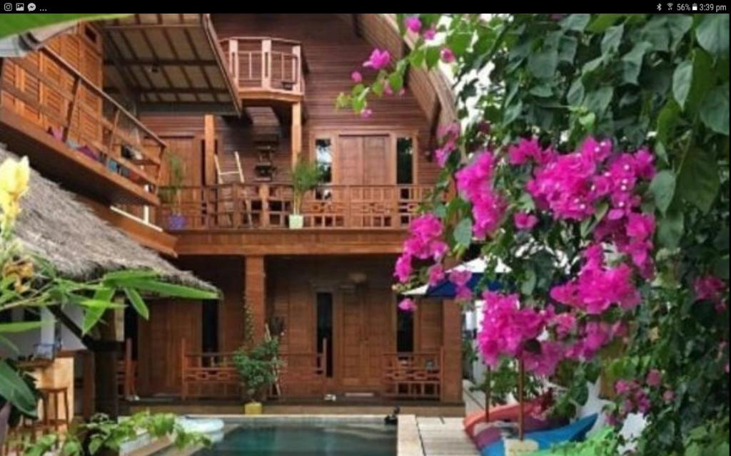 a house with a swimming pool and some pink flowers at Gili T Sugar Shack in Gili Trawangan