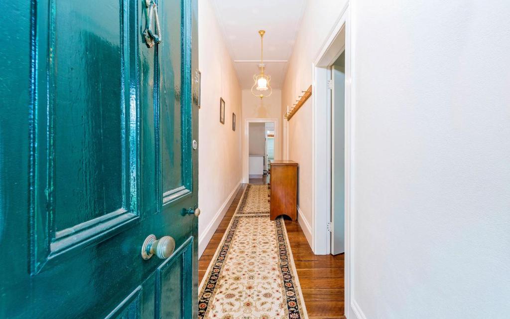 a hallway with a green door and a tile floor at Azile 1875 Heritage Victorian Duplex in Grafton