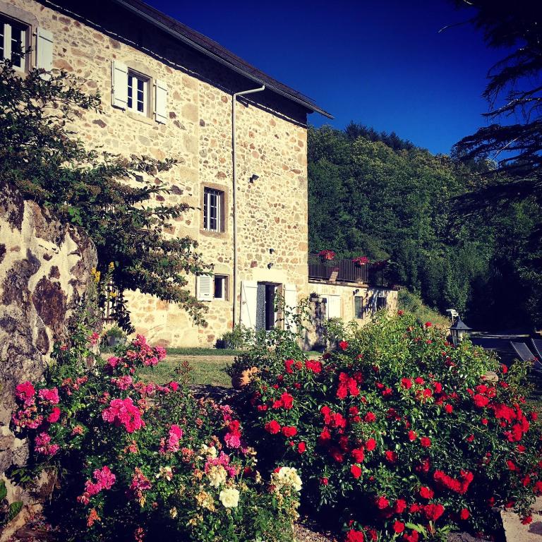 un bâtiment en pierre avec des fleurs devant lui dans l'établissement Domaine de Label, Spa, massages, à La Salvetat-sur-Agout
