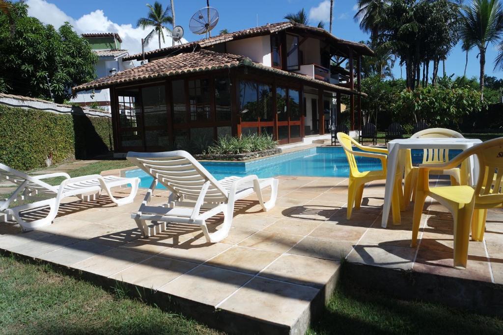 een groep stoelen en tafels naast een zwembad bij Residencial Frente a Praia in Porto Seguro