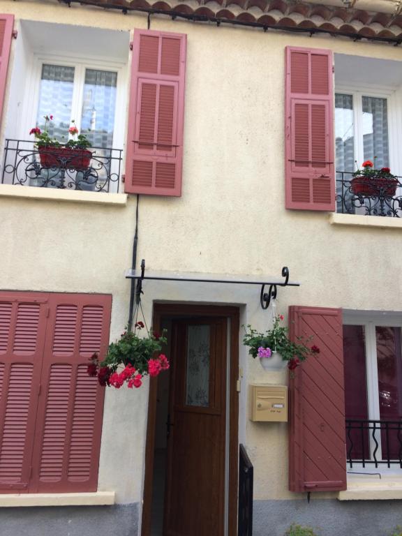 フォルカルキエにあるMaison de vacancesの窓に赤いシャッターと花を飾った家