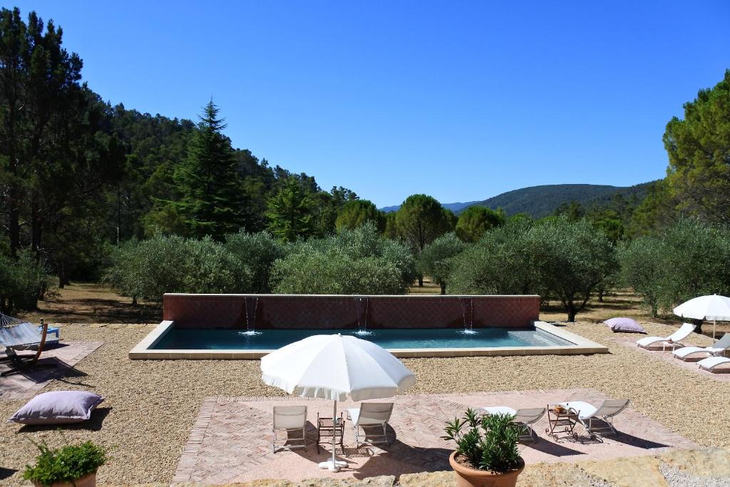 una piscina con sillas y sombrillas en un patio en La Bastide de la Provence Verte, chambres d'hôtes, en La Roquebrussanne
