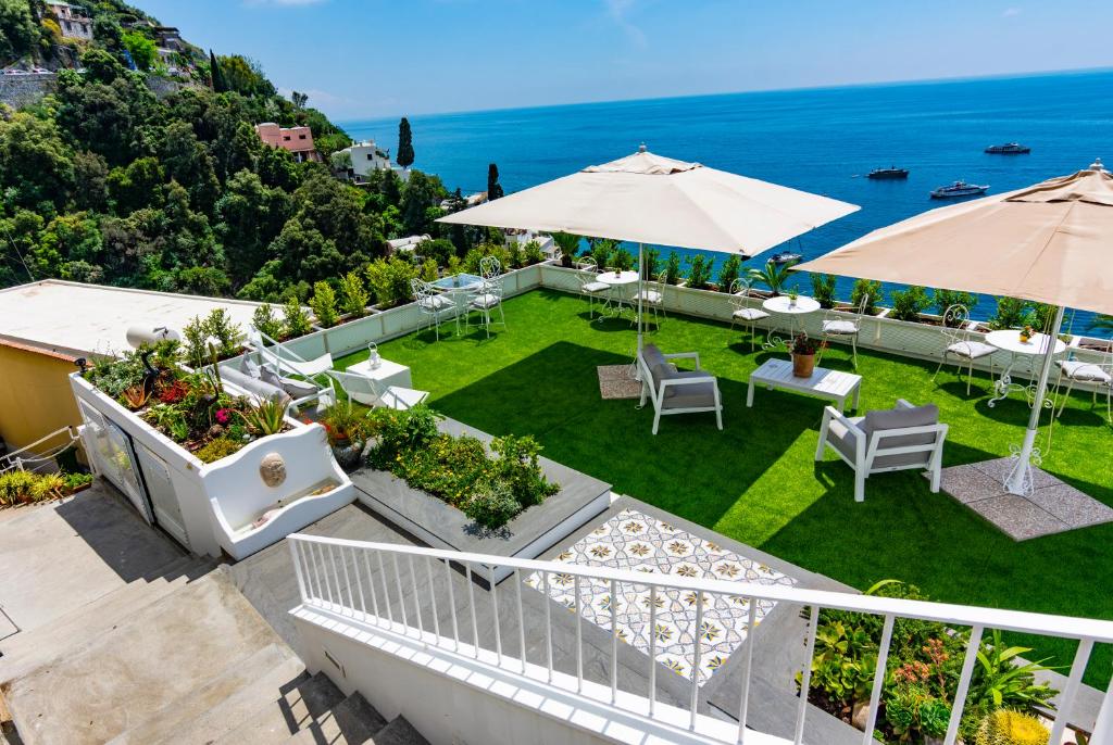 un patio esterno con tavoli, ombrelloni e l'oceano di Villa Pietra Santa a Positano