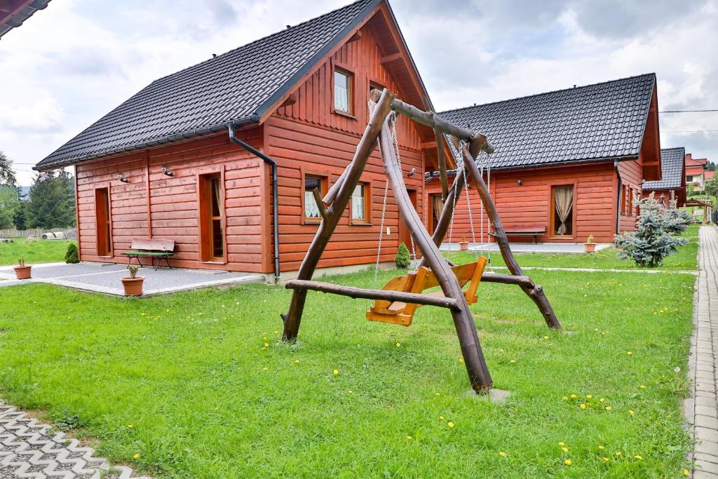a swing in front of a log cabin at Domki w Istebnej in Istebna
