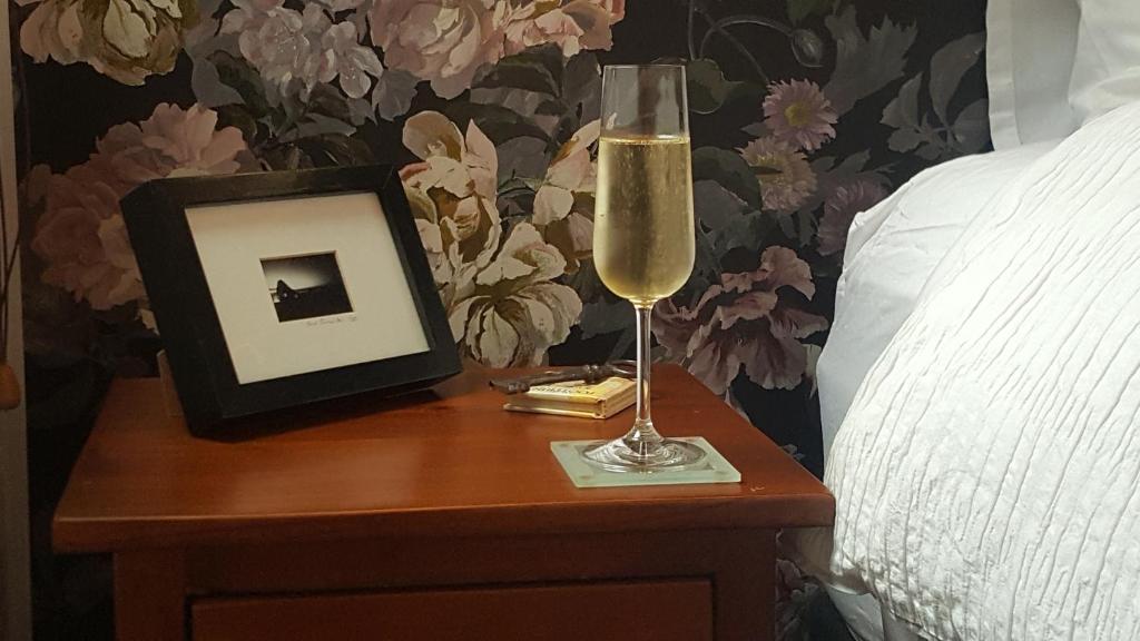 a glass of champagne on a table next to a bed at Sequoia Steps in New Plymouth