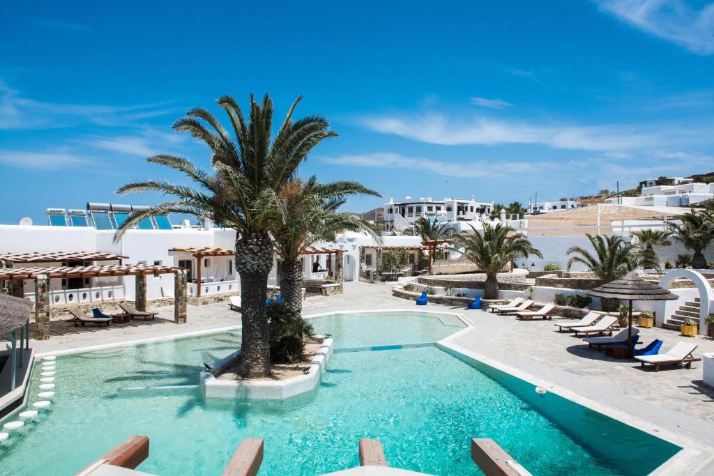 una piscina con sillas y una palmera en un complejo en Happy Apartments Mykonos, en Klouvas