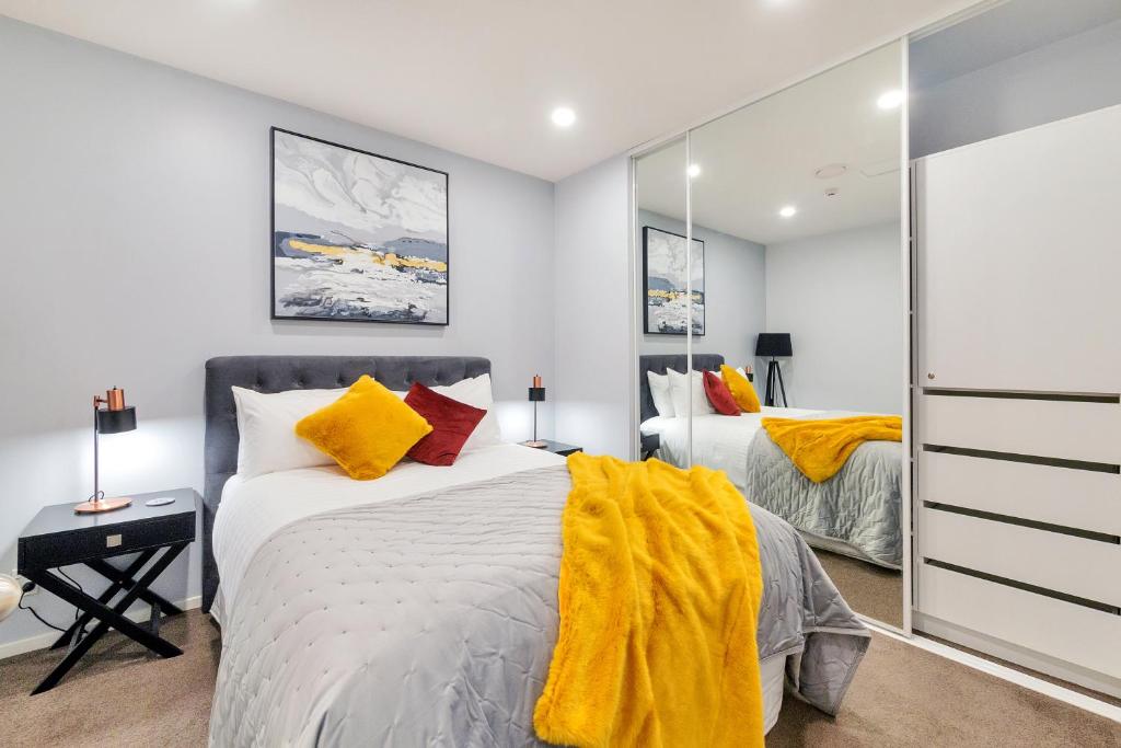 a bedroom with a bed and a mirror at Chic Metro Apartment with Free Parking and Air-con in Auckland