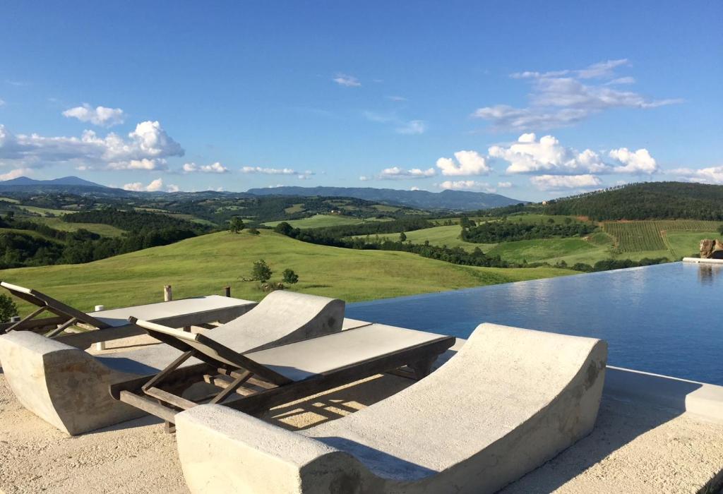 - une piscine avec des chaises longues et une vue sur les montagnes dans l'établissement Residenza d'Epoca La Commenda, à Manciano