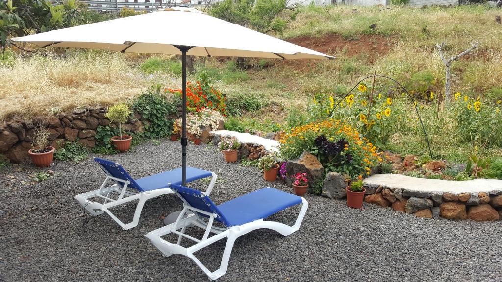 dos sillas y un paraguas y un banco y flores en Casa roko, en Puntagorda