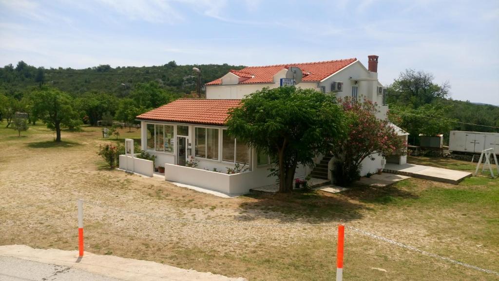 una casa con un árbol delante de un patio en Guesthouse Budima, en Banići