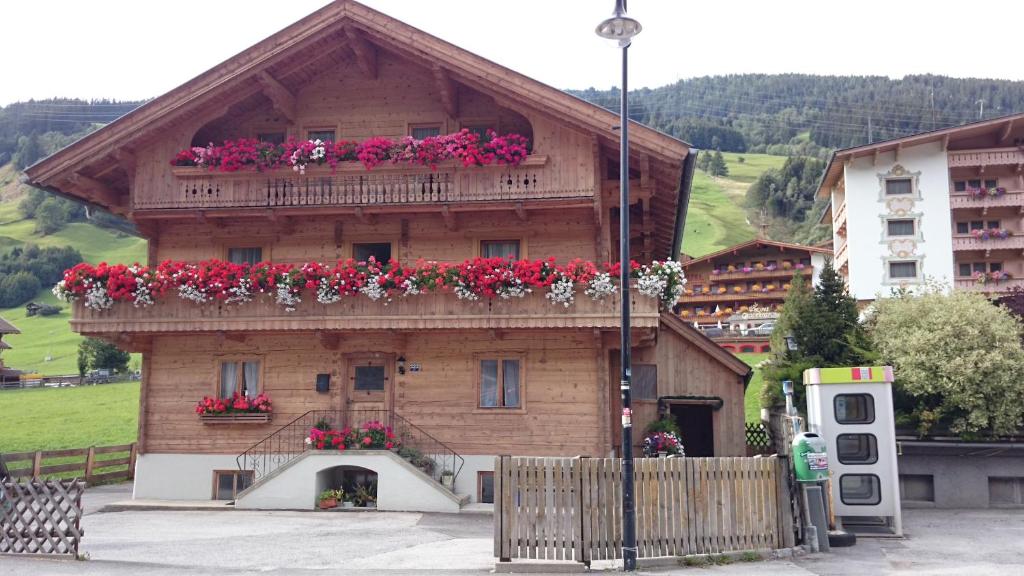 a wooden house with flowers on the top of it at Ferienwohnung Höllwarth in Gerlos