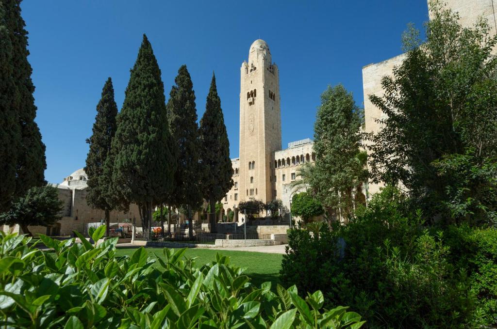 um edifício com uma torre de relógio num parque em YMCA Three Arches Hotel em Jerusalém